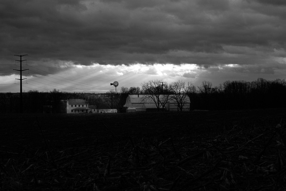 Storm and sunshine before a white barn
